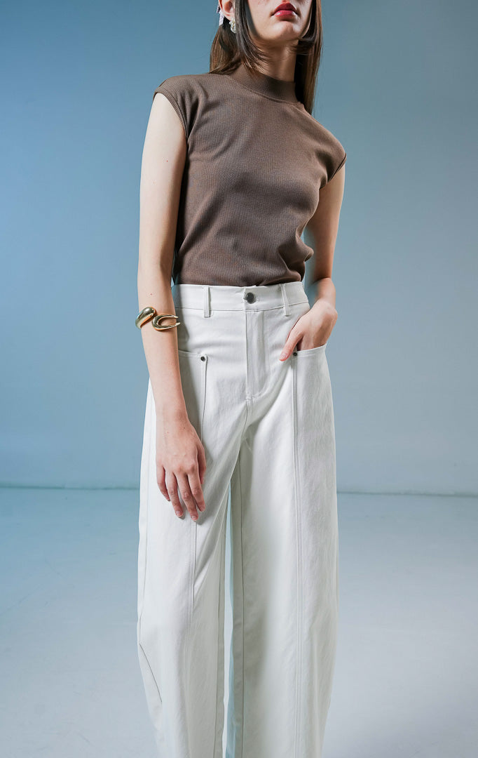 Model wanita mengenakan Eleinna Straight Leg Pants warna ivory atau putih tulang, celana panjang katun berpotongan lurus dengan detail saku depan. 