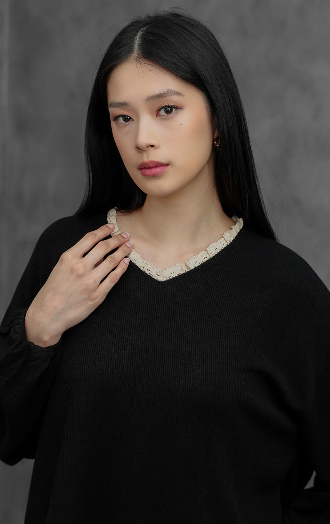 Sweter rajut wanita lengan panjang warna hitam (black) Chandria Sweater dengan potongan longgar (loose silhouette), lengan balon (balloon sleeves), dan aksen kerut renda kontras (contrast ruffle trim) di bagian leher.
