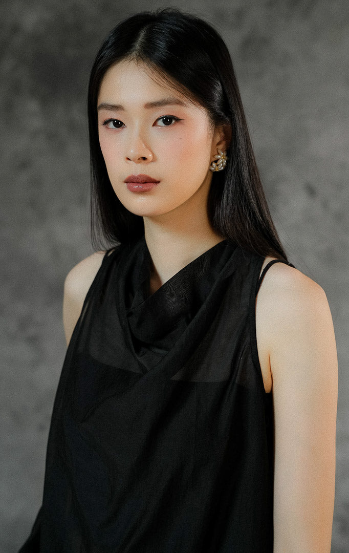 Blouse wanita tanpa lengan Charlette warna hitam polos dengan bahan transparan (sheer) yang elegan, cocok dipadukan dengan inner untuk look semi-formal.