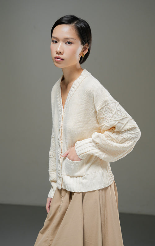 Cardigan rajut wanita Chiara Cardigan warna ivory krem muda lengan panjang bertekstur motif rajut dengan kerah V-neck, kancing depan, dan dua saku depan. 