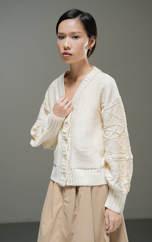 Cardigan rajut wanita Chiara Cardigan warna ivory krem muda lengan panjang bertekstur motif rajut dengan kerah V-neck, kancing depan, dan dua saku depan. 