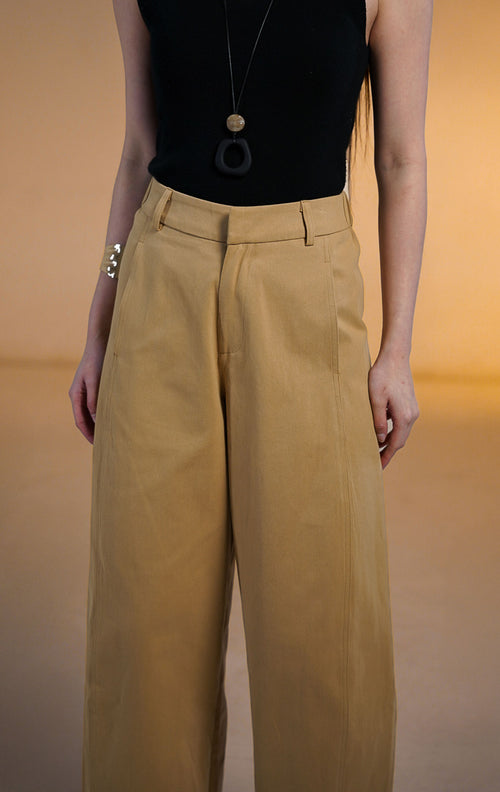 Model wanita memakai Christopher Pants Khaki, celana panjang bahan katun warna coklat muda dengan potongan barrel leg, saku samping, dan atasan hitam