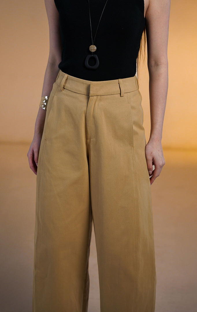Model wanita memakai Christopher Pants Khaki, celana panjang bahan katun warna coklat muda dengan potongan barrel leg, saku samping, dan atasan hitam
