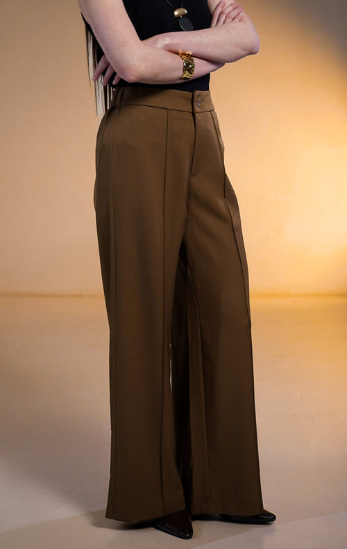 Model wanita memakai Clarence Pants Dark Brown, celana panjang coklat tua potongan lurus dengan detail jahitan tulang depan (front darts) dipadukan dengan atasan tank top hitam