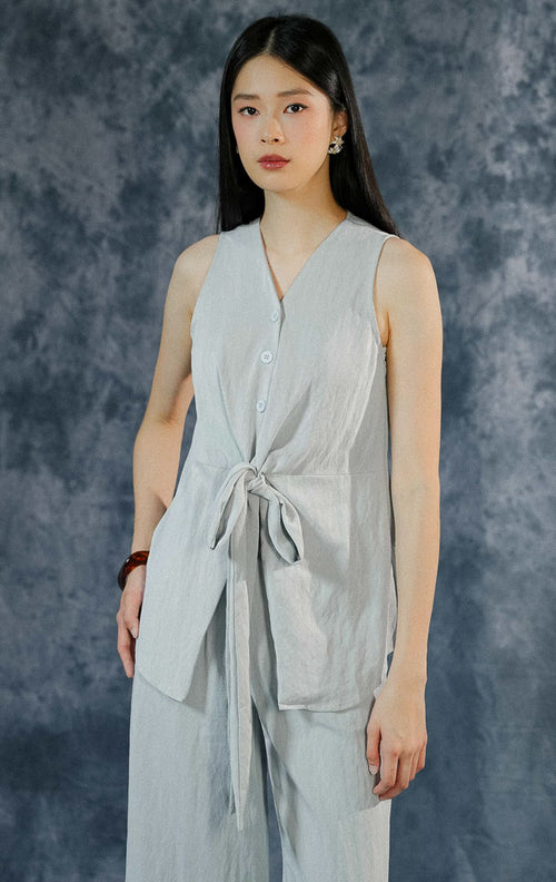 One set wanita berwarna light blue seri Collette, menampilkan atasan sleeveless berkerah rapi dengan detail tali serut pita aktif di pinggang depan.
