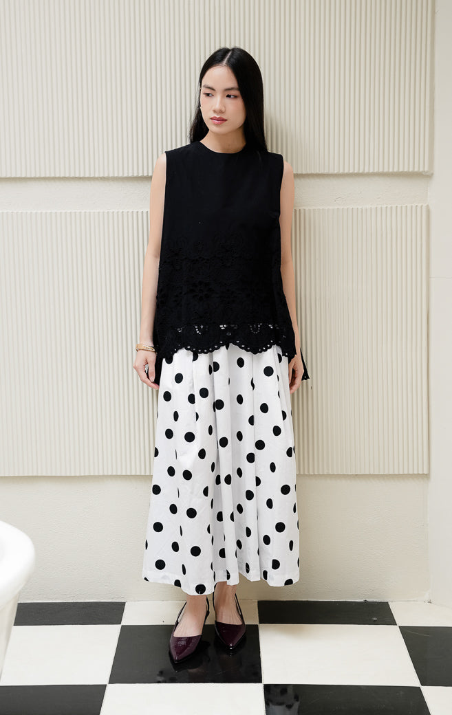 Atasan blouse tanpa lengan wanita warna hitam Cyrus Top dengan detail bordir krawang broderie anglaise di bagian bawah dan kancing belakang. 