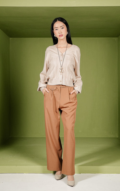 Kardigan rajut wanita Daliya Cardigan warna beige polos dengan kerah V-neck, kancing depan, dan detail tekstur rajutan bermotif gelombang pada area depan bawah.