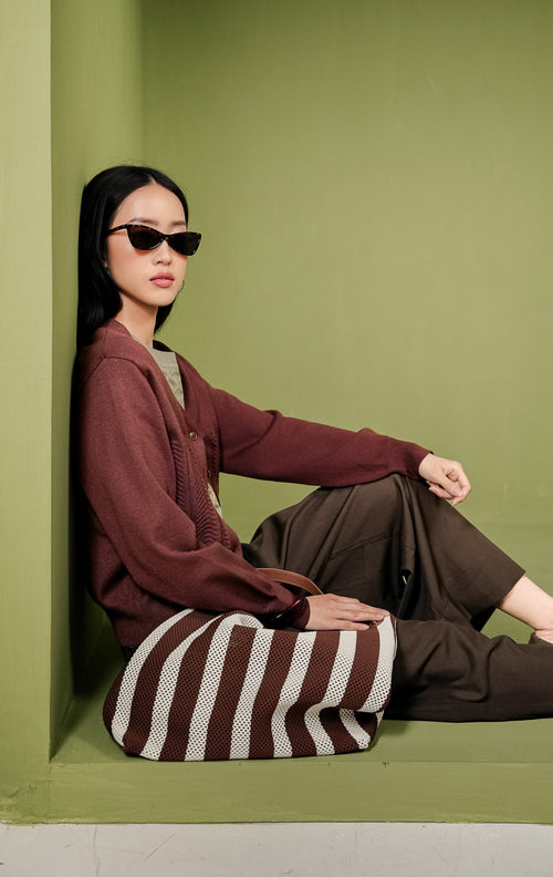 Kardigan rajut wanita Daliya Cardigan warna cokelat tua (dark brown) polos dengan kerah V-neck, kancing depan, dan detail tekstur rajutan bermotif gelombang pada area depan bawah. 