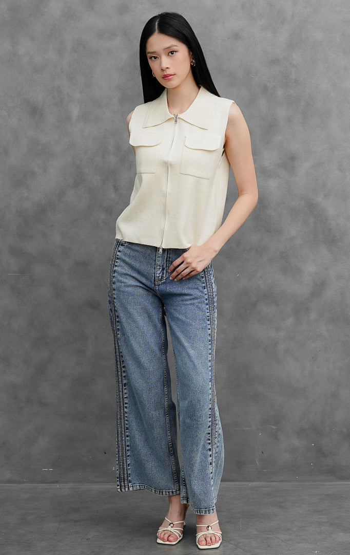 Rompi rajut (knit vest) wanita tanpa lengan warna krem muda (ivory) Danielle Vest dengan kerah lancip (pointed collar), bukaan resleting depan (front zip closure), dan dua saku tempel fungsional di dada.