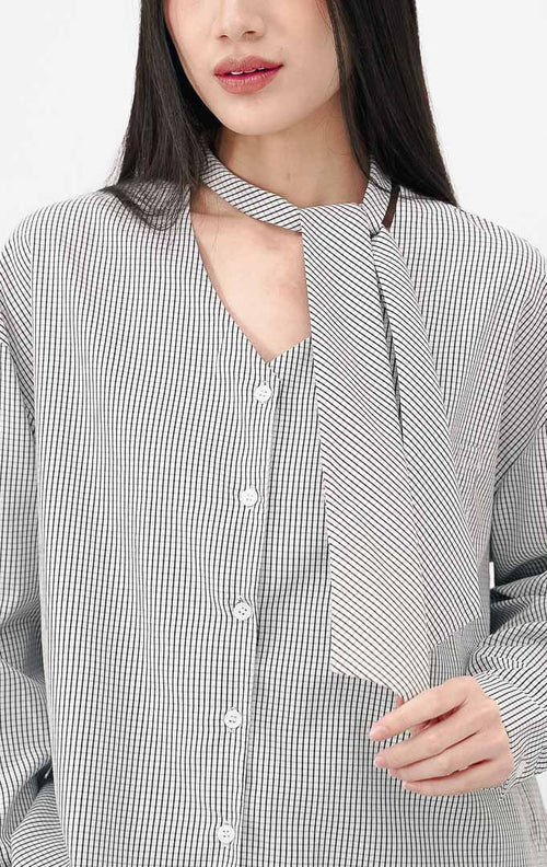 Model mengenakan Daverna Top warna white, atasan lengan panjang motif gingham (kotak kotak kecil) hitam putih dengan detail kerah model syal yang modis.