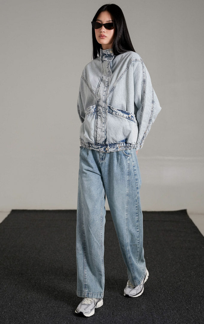 Derry Oversized Jacket warna light denim (biru muda) dengan detail kerah tinggi dan saku depan, dipadukan bergaya denim-on-denim dengan celana jeans senada dan sneakers.