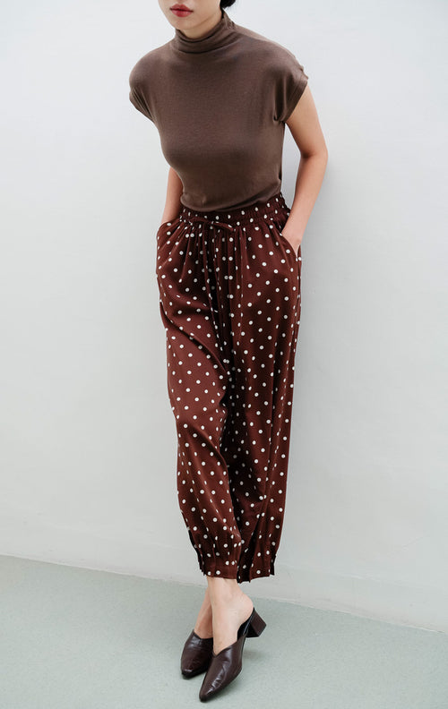 Celana panjang wanita warna cokelat tua (dark brown) Dotsie Pants berbahan satin halus motif polkadot dengan potongan relaxed fit dan saku samping.