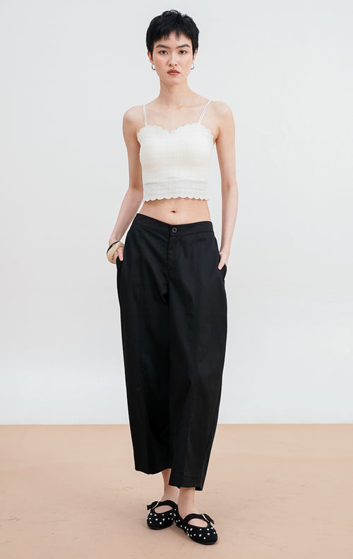 Model mengenakan Dottie Pants warna black, celana kain panjang siluet lurus (straight leg) dengan detail kancing depan dan saku samping yang rapi.