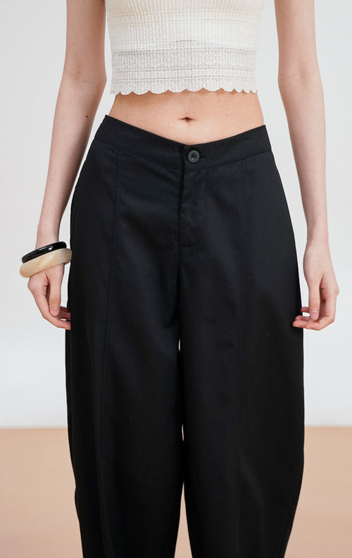 Model mengenakan Dottie Pants warna black, celana kain panjang siluet lurus (straight leg) dengan detail kancing depan dan saku samping yang rapi.