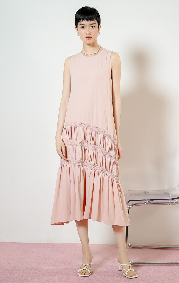 Model wanita mengenakan Ravena Shirred Bodice Drop-Tier Maxi Dress warna pink, gaun panjang dress tanpa lengan wanita warna merah muda dengan detail aksen serut karet smok miring bertingkat di rok. 
