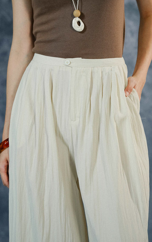 Celana panjang wanita Echo warna ivory dengan cutting loose pants kulot, berbahan crinkle-polyester flowy, dilengkapi saku samping dan resleting depan.