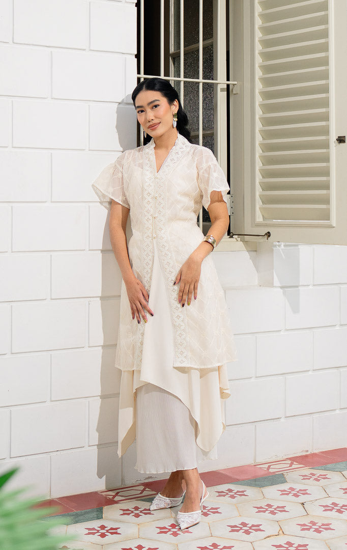 EID Atelier Skirt Ivory, rok bawahan wanita warna putih gading dengan 
desain tumpuk layer, bagian dalam bahan plisket lipit dan bagian luar 
bahan polos dengan potongan asimetris melengkung.