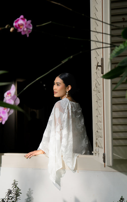 EID Jina Outer White, luaran model cape wanita bahan organza jacquard 
warna putih bersih dengan motif bunga timbul 3D dan detail kancing di 
bahu