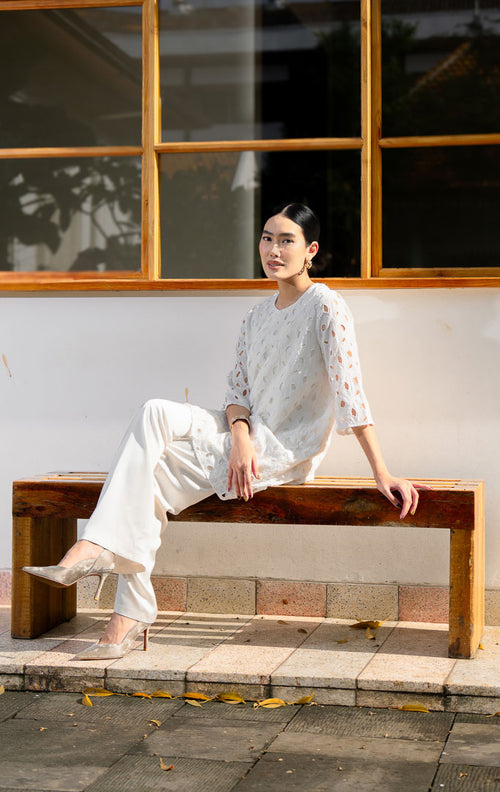 EID Latifa Top White, atasan wanita warna putih bersih bahan katun dengan 
motif bordir eyelet berlubang dan detail kancing mutiara miring asimetris di 
depan.