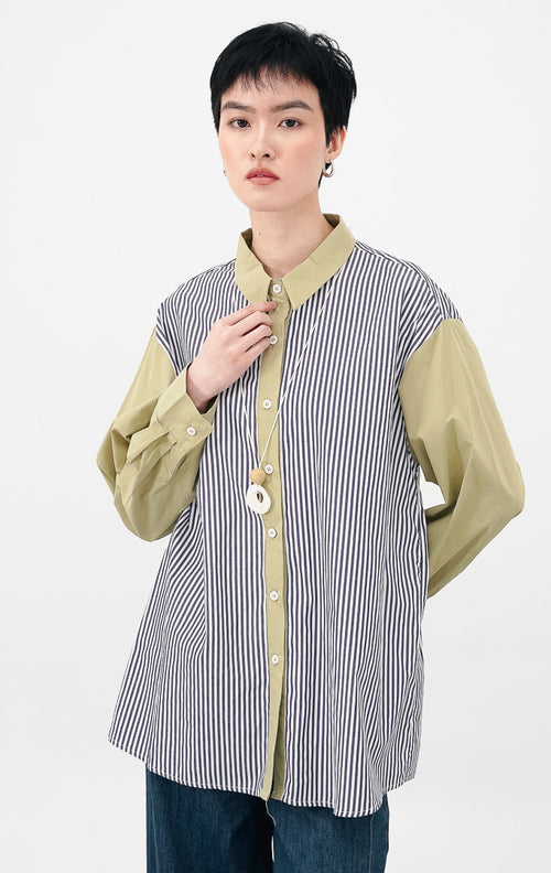 Close up model mengenakan Emerald Top warna sage, menampilkan detail kemeja motif garis vertikal biru putih dengan kerah dan bagian kancing berwarna sage green.