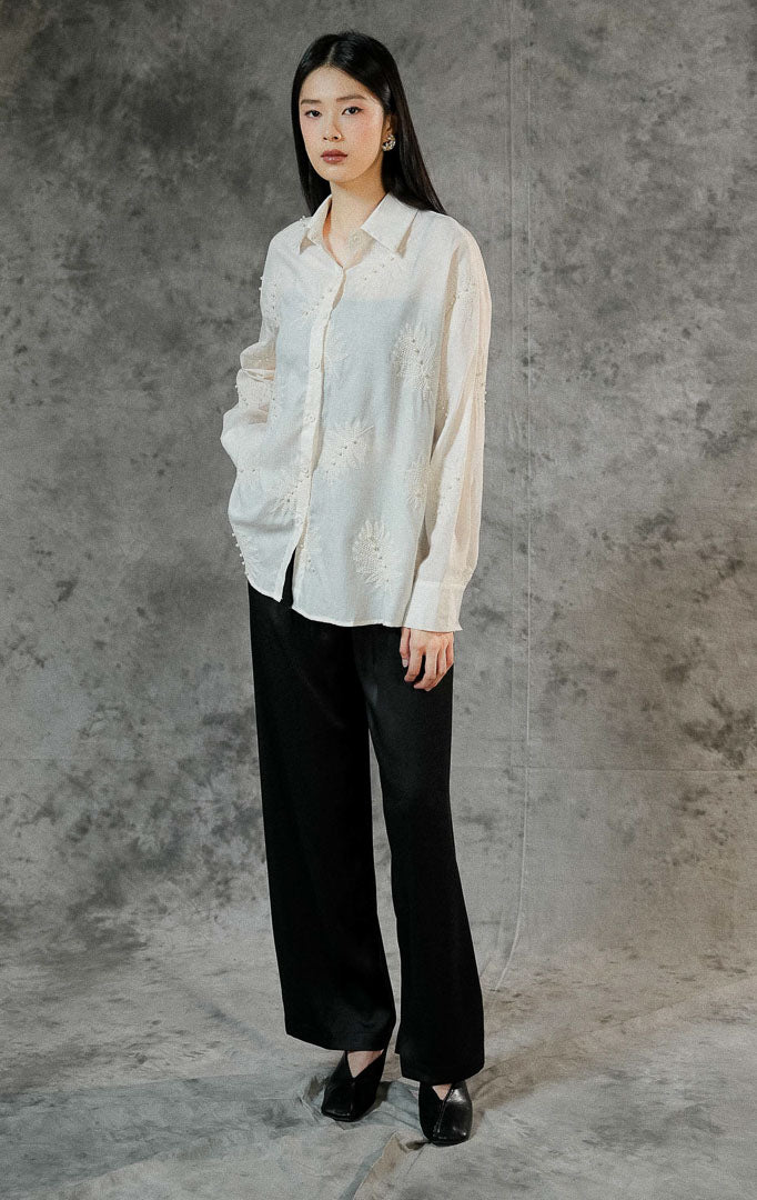 Atasan kemeja lengan panjang wanita Emmett warna ivory dengan motif bordir bunga (floral embroidery), detail manik mutiara, dan kerah formal.