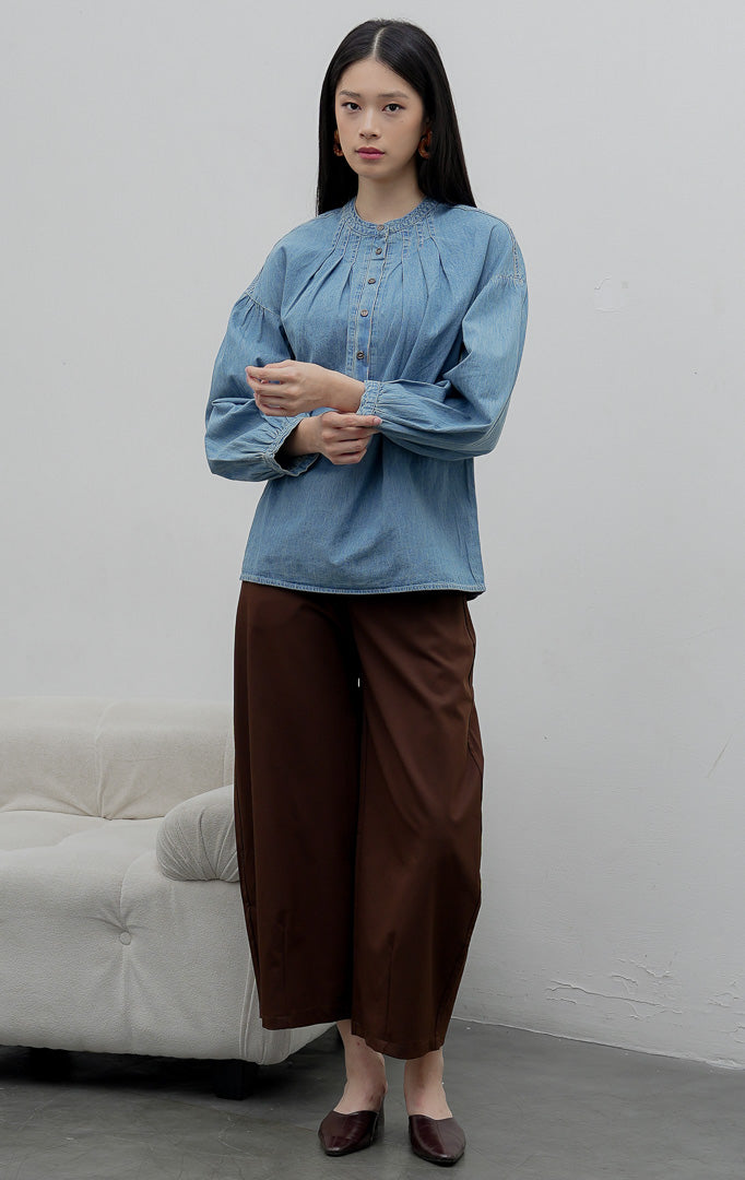 Atasan denim chambray wanita lengan panjang warna biru medium (denim) Eriu Top berbahan non-stretch dengan aksen lipit (pleated design) dan bukaan kancing setengah (half-placket)
