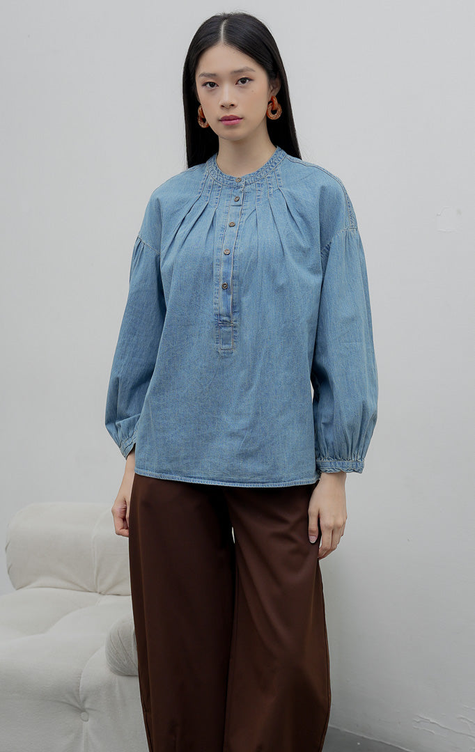 Atasan denim chambray wanita lengan panjang warna biru medium (denim) Eriu Top berbahan non-stretch dengan aksen lipit (pleated design) dan bukaan kancing setengah (half-placket)