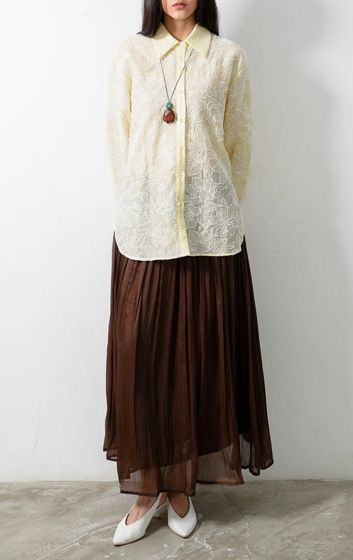 Kemeja wanita lengan panjang warna kuning muda (butter yellow) Everlynne Top berbahan tekstur ringan (lightweight textured fabric) dengan kerah kemeja (collared neckline), bukaan kancing depan, dan detail bordir motif bunga (tonal floral embroidery). 

