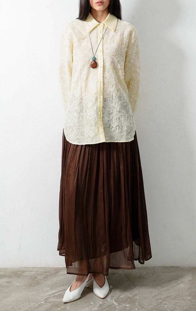 Kemeja wanita lengan panjang warna kuning muda (butter yellow) Everlynne Top berbahan tekstur ringan (lightweight textured fabric) dengan kerah kemeja (collared neckline), bukaan kancing depan, dan detail bordir motif bunga (tonal floral embroidery). 

