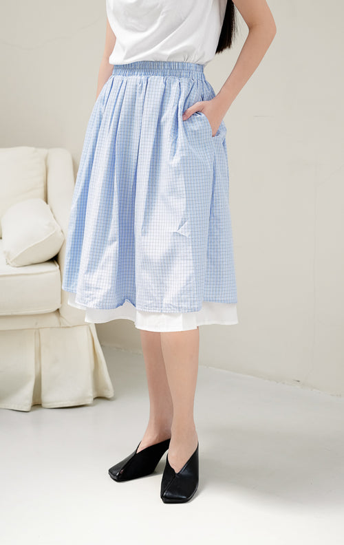 Rok midi wanita Feliciona Skirt warna light blue (biru muda) bermotif kotak windowpane check dengan potong layered flare dan pinggang karet.
