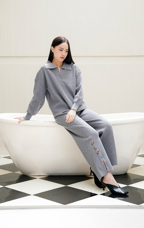 One set pakaian wanita Fernanda Set warna grey abu-abu berbahan rajut (knit) halus, terdiri dari atasan lengan panjang kerah v-neck dan celana rajut panjang detail kancing serta belahan slit. 
