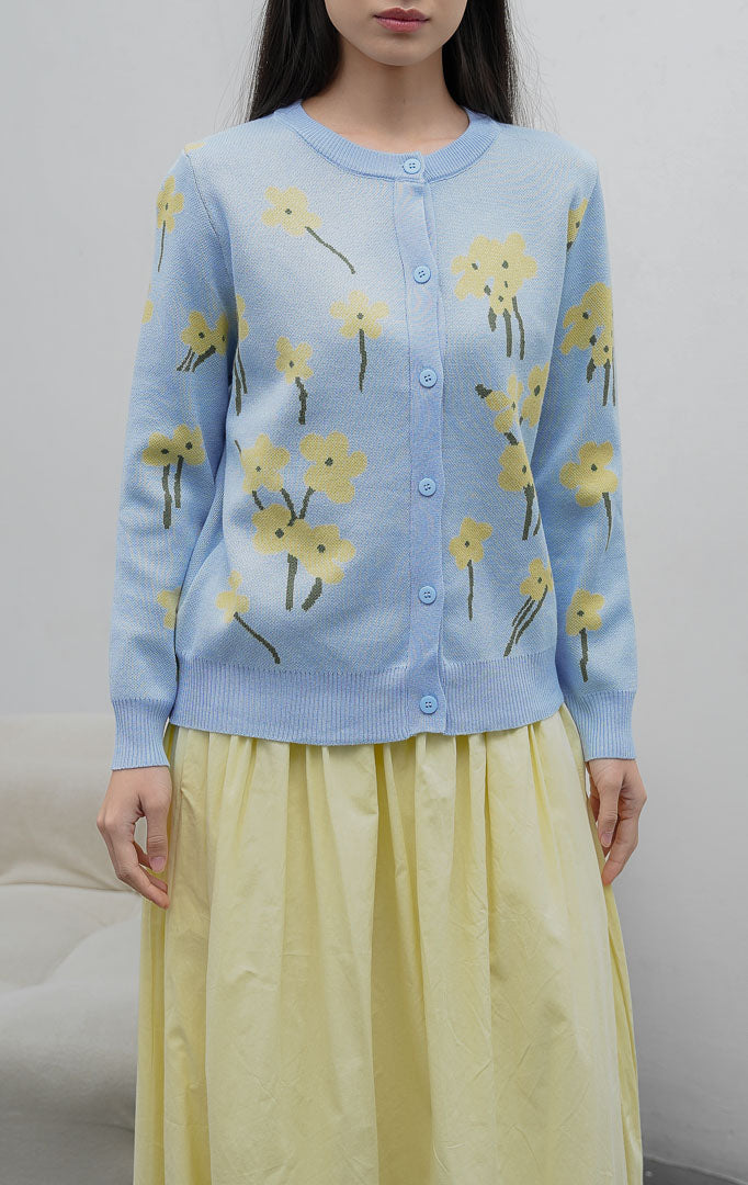 Sweter rajut wanita lengan panjang warna biru muda (light blue) Fleur Sweater dengan motif bunga (floral print), kerah bulat, dan kancing depan.