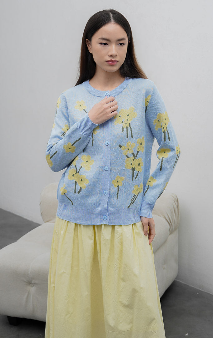 Sweter rajut wanita lengan panjang warna biru muda (light blue) Fleur Sweater dengan motif bunga (floral print), kerah bulat, dan kancing depan.