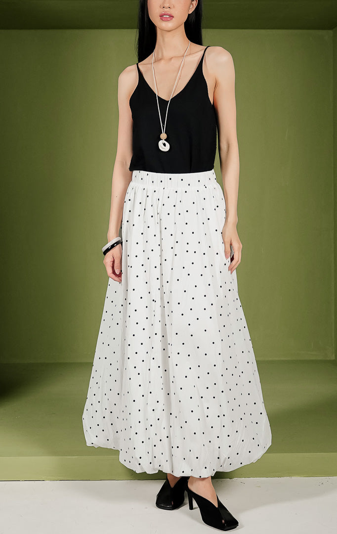 Rok midi wanita Florence Skirt siluet balon bervolume warna putih dengan motif polka dot hitam kecil di seluruh bagian, dilengkapi dengan pinggang karet elastis.