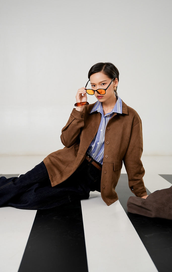 Jaket suede wanita Frances Jacket warna Brown dengan detail kerah, kancing depan senada, saku dengan tutup (flap pockets), dan material suede bertekstur lembut dari This Is April. 