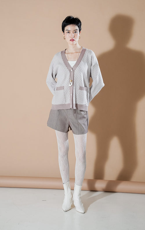 the Gilda brown patterned knit cardigan featuring a V-neck, button-down front, and pockets, styled with casual shorts.