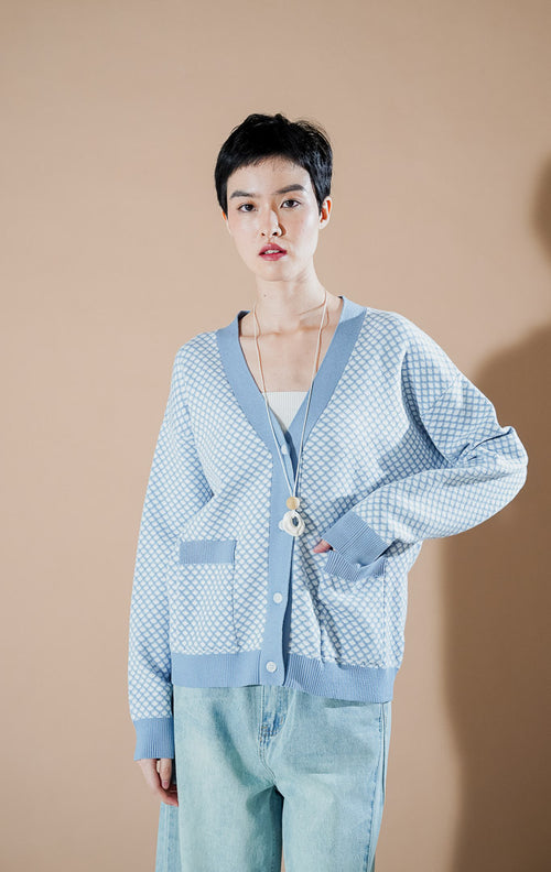 Model wanita mengenakan Gilda Patterned Knit Cardigan warna Blue, kardigan rajut v-neck dengan motif ketupat kecil (diamond pattern) dan saku depan dari This Is April.