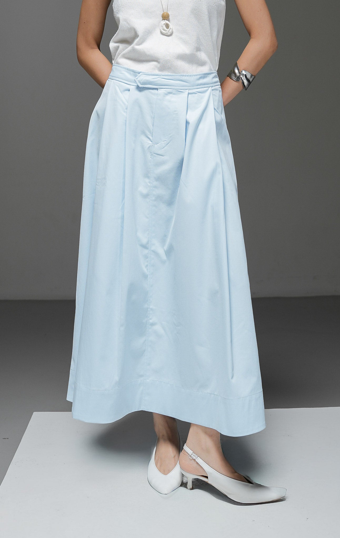Rok midi wanita Gracelyn Skirt warna light blue biru muda model A-line high waist dengan detail lipat pleat di depan dan kantong samping. 
