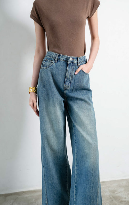 Celana jeans denim wanita warna biru (blue denim jeans) Grine Pants dengan cucian pudar lembut (softly faded wash), pinggang tinggi sedang (mid-rise waist), konstruksi lima saku tradisional, dan siluet lurus (straight-leg silhouette). 

