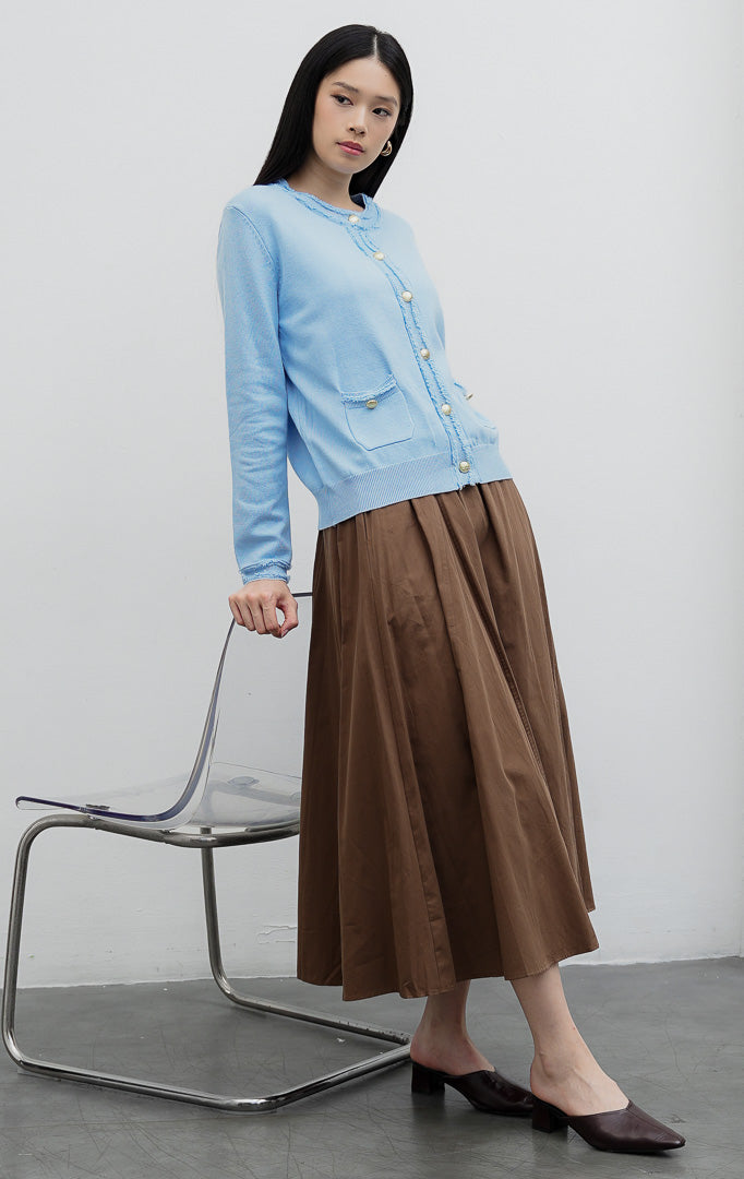 Kardigan rajut wanita lengan panjang warna biru muda (light blue) Guilin Cardigan dengan detail rumbai (fringe trims), saku depan fungsional, dan kancing emas. 