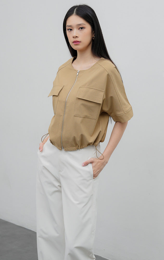 Atasan wanita cargo warna khaki Hale Top berbahan campuran katun-poliester dengan resleting depan (zip-front), saku dada, dan tali serut bagian bawah (adjustable hem string).