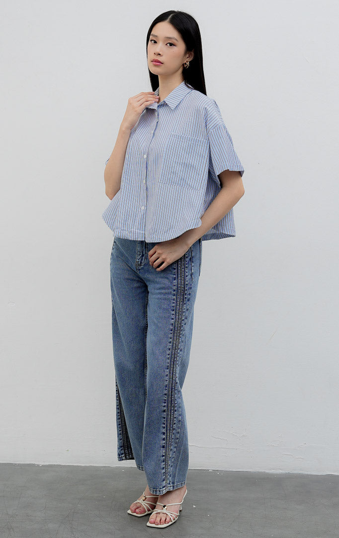 Kemeja katun wanita lengan pendek potongan boxy warna biru (blue) Hampton Top berkerah (spread collar) dengan motif garis vertikal (striped pattern), kancing depan, dan saku dada.