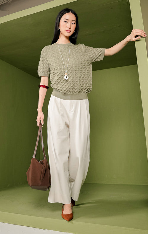 Atasan rajut wanita Harper Top warna olive (hijau zaitun) lengan pendek, dilengkapi kerah bulat (crew neck) beraksen rib, serta dihiasi motif rajutan bertekstur bentuk diamond atau wajik di seluruh permukaannya.