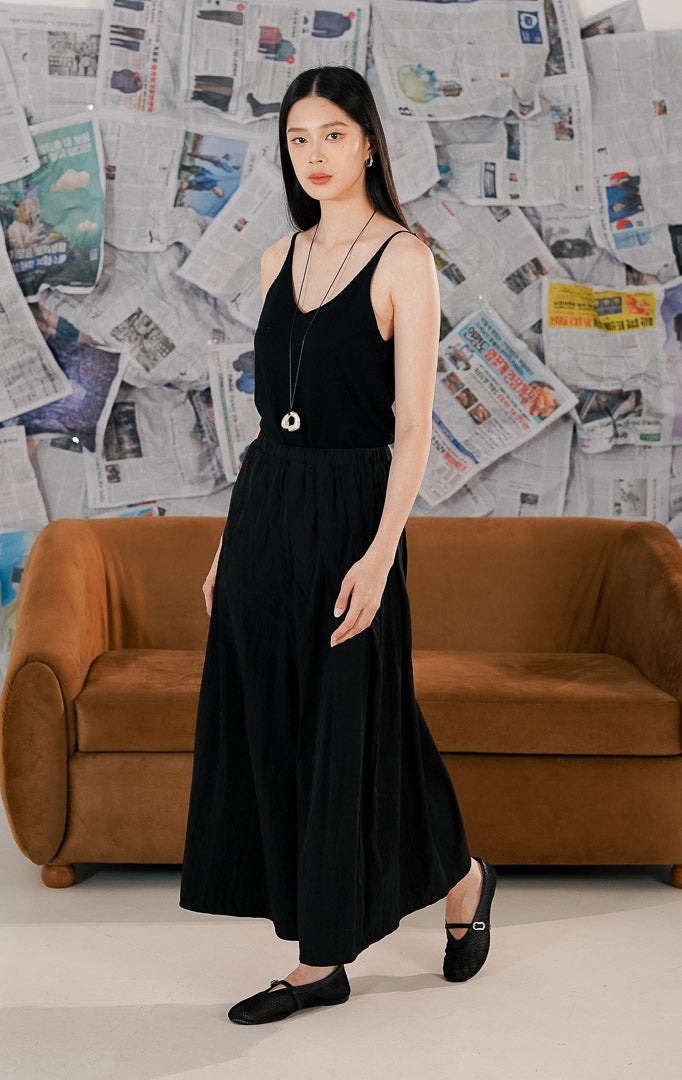 Wanita mengenakan Harrison Pants warna beige cream, celana kulot panjang model rok celana (skirt pants) dengan pinggang karet kerut yang nyaman dan bahan flowy.