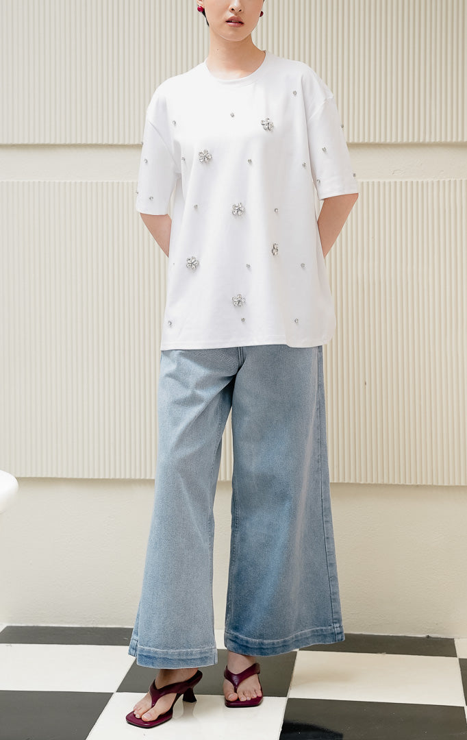 Kaos oversized wanita warna putih Haru Top dengan detail hiasan kristal floral rhinestone, kerah bulat, dan model santai bergaya streetwear.