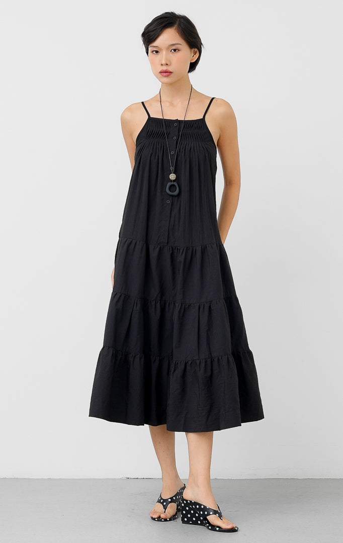 Maxi dress panjang wanita warna hitam Hathaway Dress berbahan katun dengan detail smocked yoke di dada, tali spageti (adjustable straps), dan gaun berundak (tiered silhouette).