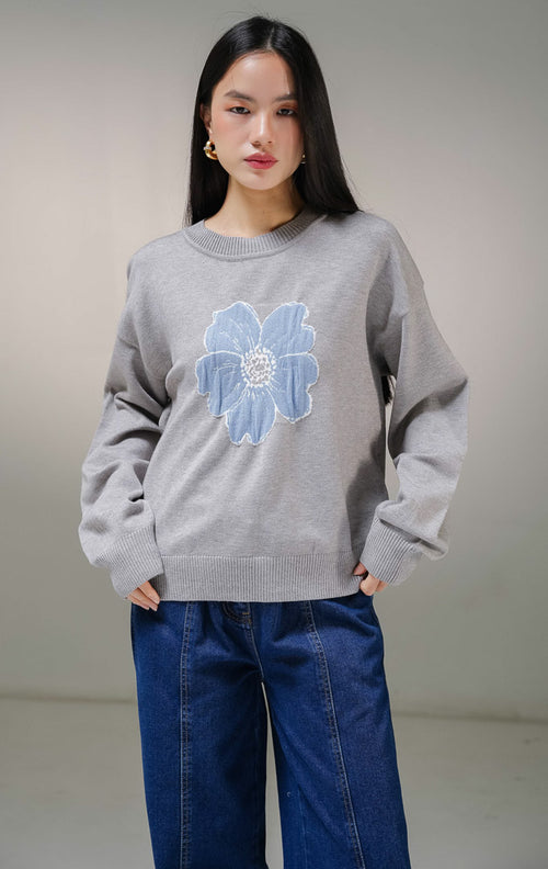 Atasan sweater rajut lengan panjang wanita This Is April Samantha Sweater warna abu-abu, model kerah bulat dengan detail motif grafis bunga besar warna biru di bagian tengah depan. 