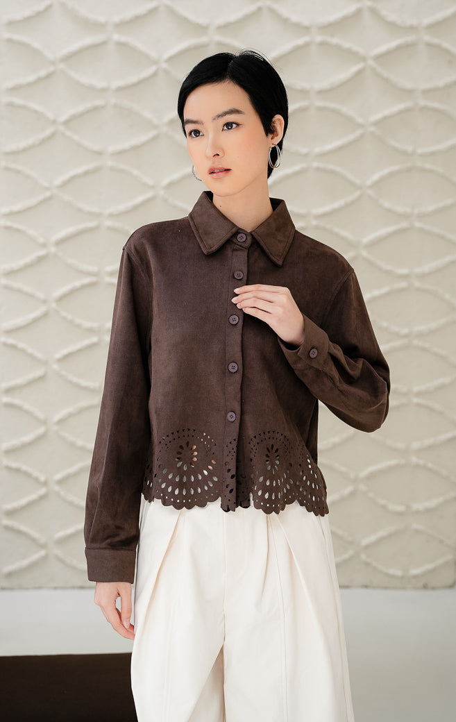 Atasan wanita Holley Top warna dark brown (cokelat tua) berbahan suede dengan kancing depan dan detail ukiran laser-cut/eyelet di hem bawah style classic & modern. 