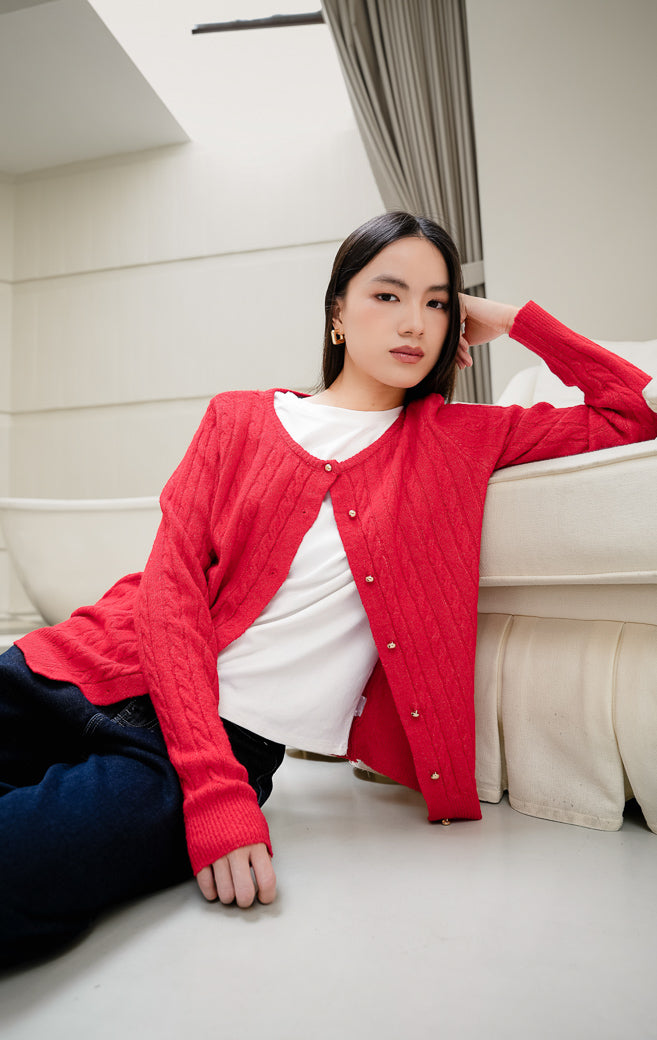Cardigan rajut wanita Issac Cardigan warna red (merah) motif cable knit tekstur lembut dengan aksen kancing emas (gold button) dan kerah round-neck. 