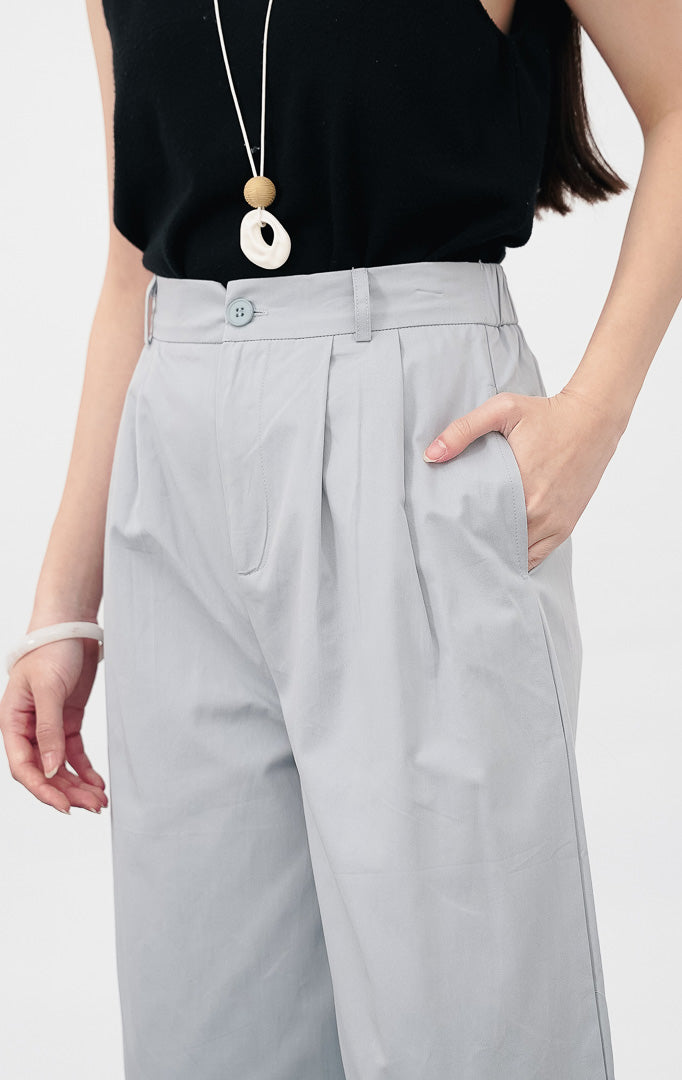 Model mengenakan Ivana Pants warna blue, celana kain wide leg dengan detail lipit depan, kancing senada, dan saku samping, dipadukan dengan sepatu flat putih.